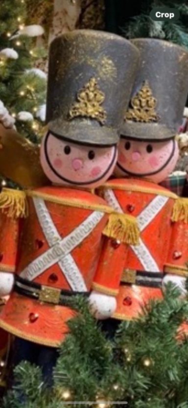 Two toy soldiers in red and white uniforms with tall grey hats, surrounded by festive decorations.
