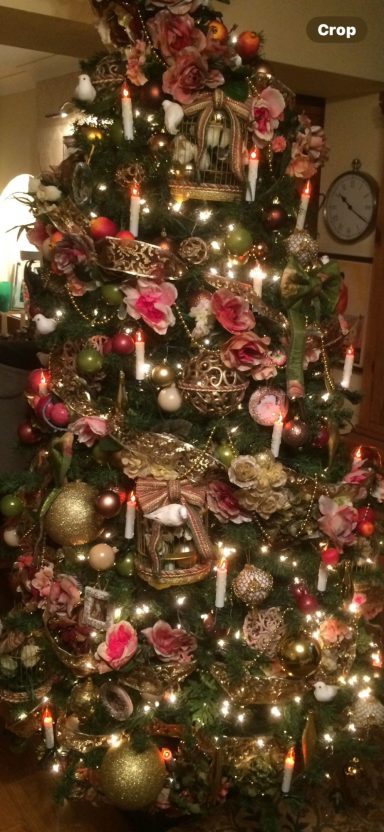 A beautifully decorated Christmas tree with pink and gold ornaments and twinkling lights.