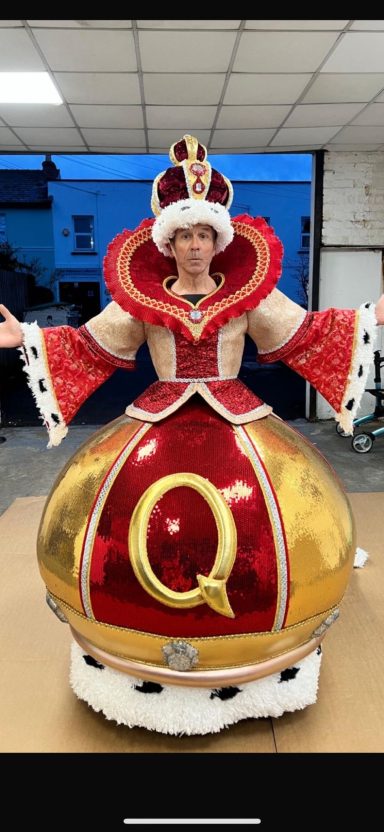 Pantomimes A performer in an elaborate costume resembling a royal figure with a large skirt and crown.
