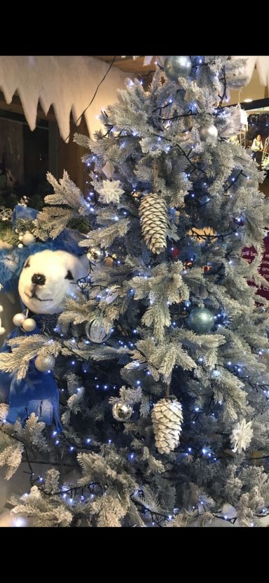 A decorated Christmas tree with silver ornaments and blue accents.