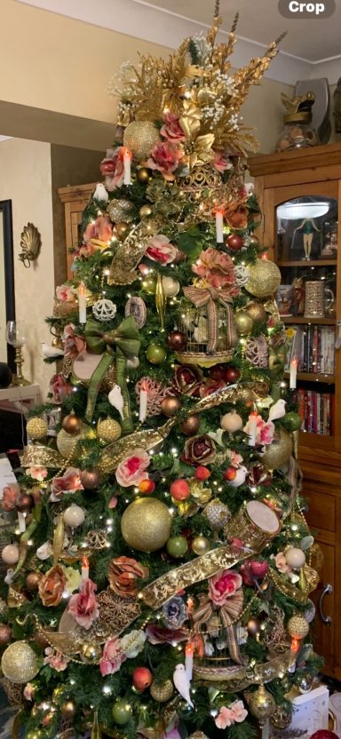 A beautifully decorated Christmas tree adorned with ornaments, ribbons, and a golden topper.