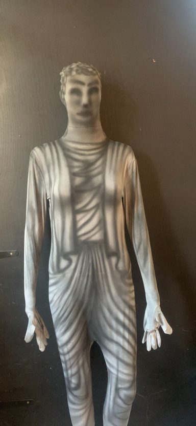 A grey, striped mannequin in a standing pose with a neutral expression.