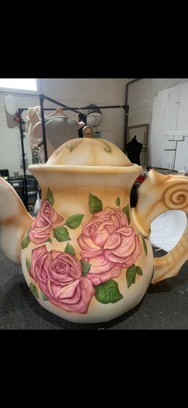 Ceramic teapot adorned with pink and lavender roses on a cream background.