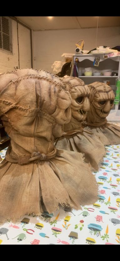 Three textured, brown sculptures resembling animal heads on a patterned tablecloth.
