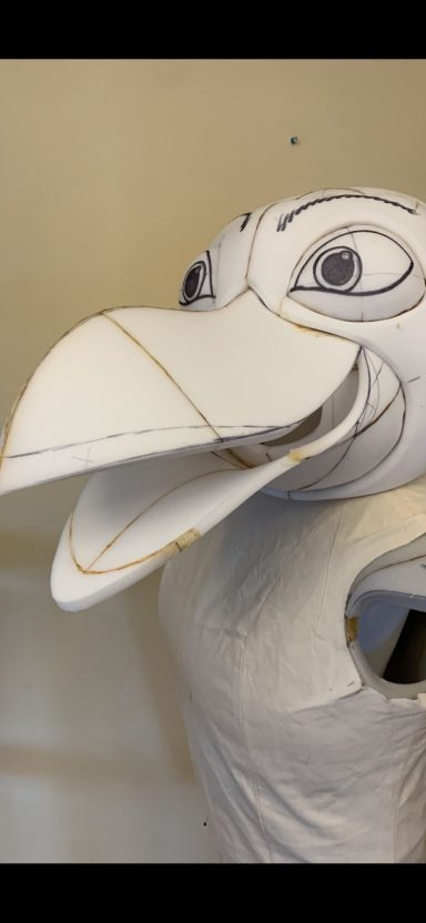 White paper mâché bird puppet head with exaggerated features and open beak.