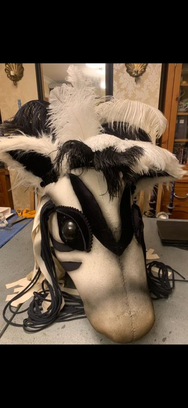 A detailed fursuit head of a black and white animal with large expressive eyes.