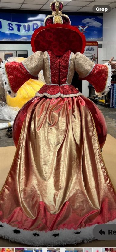 A queen costume featuring a red and gold gown with a full skirt and ornate details.