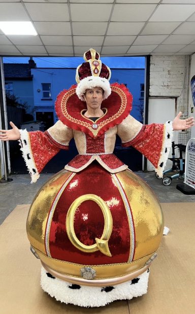 Person dressed in a large, ornate queen costume with red and gold details.