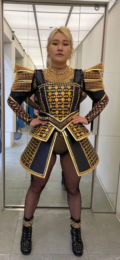 Person in a striking gold and black patterned costume with bold shoulder details.