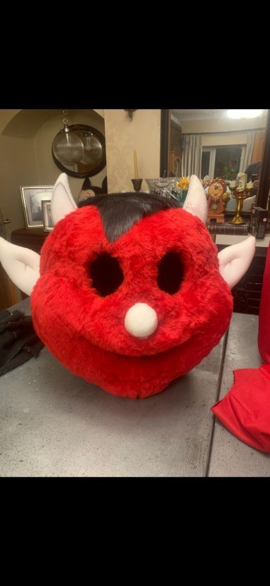 A large red devil mask with a round face, white ears, and a white nose.