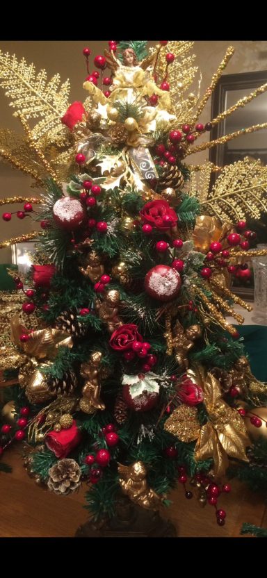 Decorated Christmas tree with gold, red, and green ornaments and festive foliage.