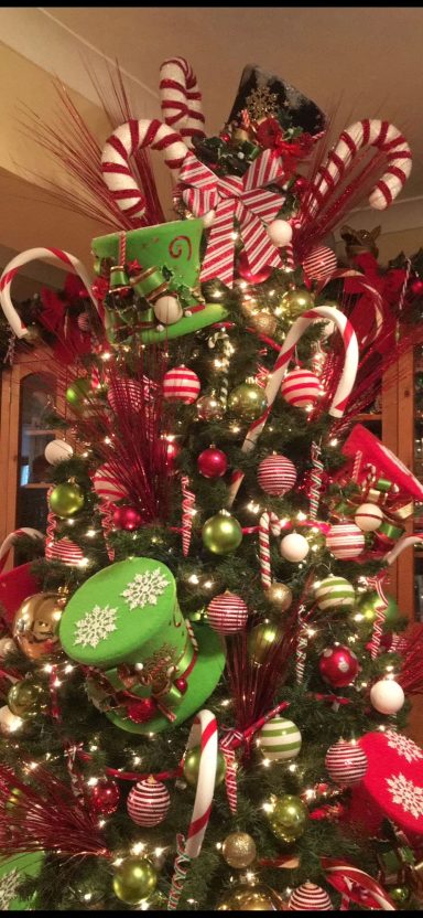 A vibrant Christmas tree decorated with red and green ornaments, candy canes, and ribbons.
