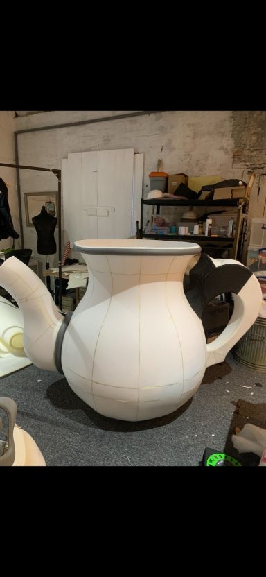 A large teapot shaped like a cow with a black and white design.